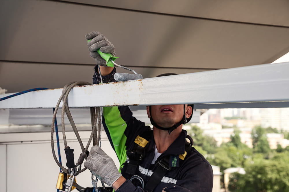 Técnico especializado asegurado con arnés trabajando en altura.